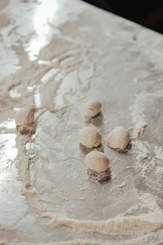 a couple of doughnuts sitting on top of a counter, inspired by Antoni Tàpies, trending on pexels, flour dust, puffballs, silver，ivory, five planets