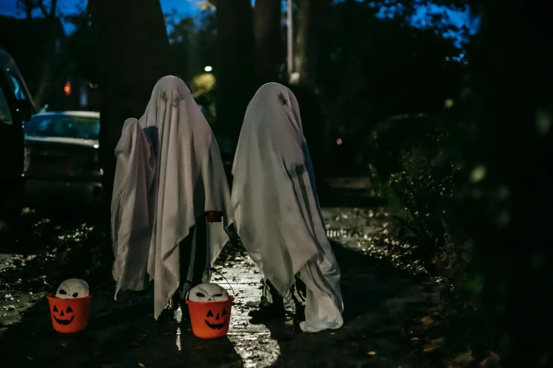 a couple of people that are standing in the rain, halloween decorations, wearing white cloths, unsplash photo contest winner, bags on ground