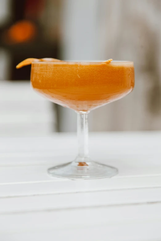 a close up of a drink in a glass on a table, inspired by Jacopo Bellini, orange body, front profile, spirited, honeysuckle