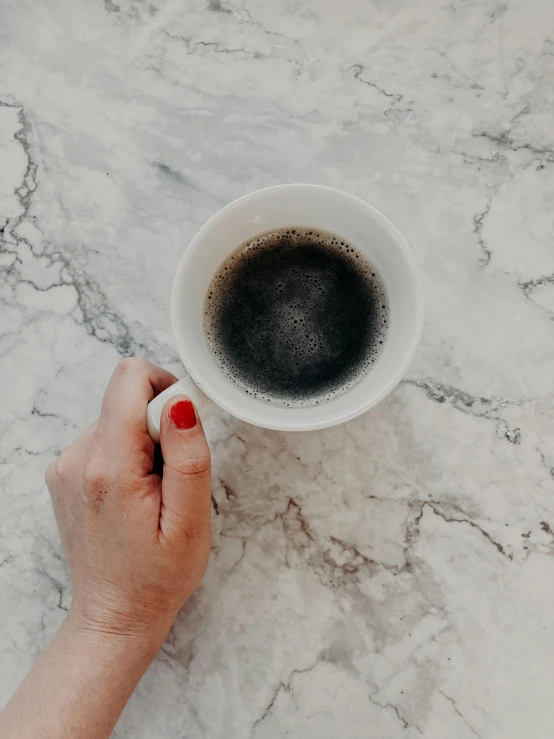 a person holding a cup of coffee on a marble table, by Lucia Peka, black marble, ((oversaturated)), promo image