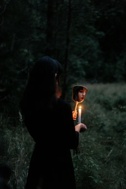 a woman holding a candle in a dark forest, an album cover, inspired by Elsa Bleda, pexels contest winner, surrealism, looking into a mirror, instagram post, profile pic, broken mirror