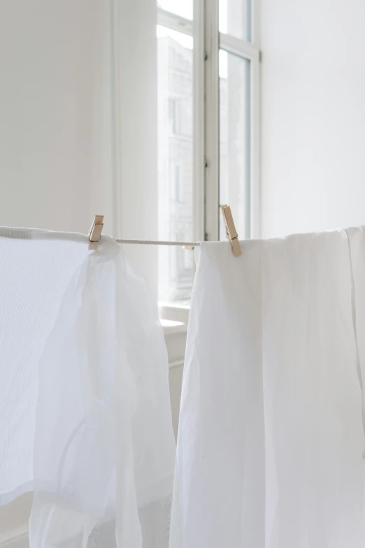 clothes hanging on a clothes line in front of a window, inspired by Eero Järnefelt, made of lab tissue, white sheets, in a white room, subtle detailing