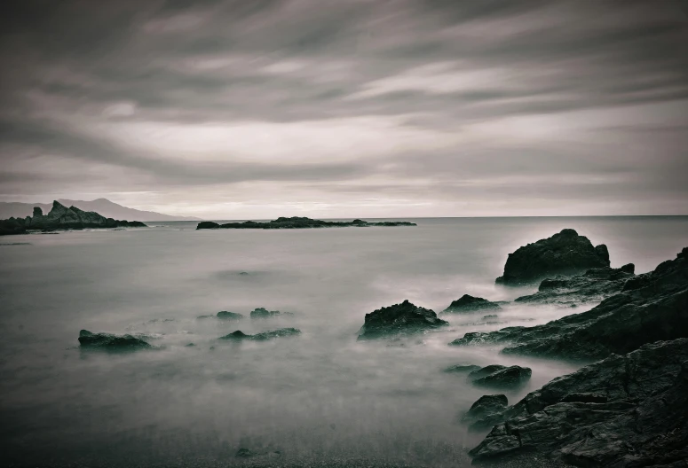 a black and white photo of rocks in the ocean, unsplash, tonalism, medium format, pembrokeshire, ocean in the distance, medium format photography