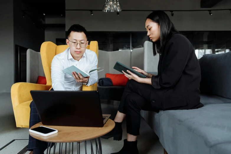 a man and a woman sitting on a couch looking at a laptop, pexels contest winner, gutai group, avatar image, asian female, wearing business casual dress, maintenance photo