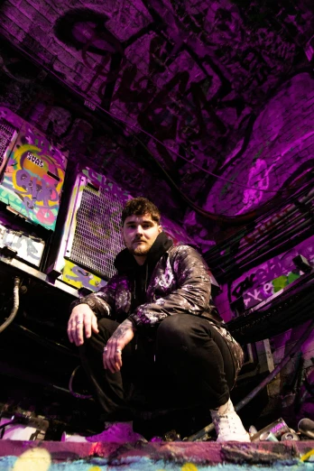 a man sitting on the ground in a purple room, a portrait, unsplash, graffiti, andy milonakis, hero pose colorful city lighting, lil peep, official photo