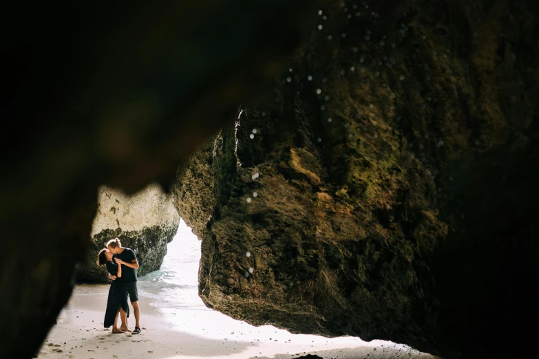 a couple standing next to each other on a beach, by Jessie Algie, unsplash contest winner, inside a humongous cave, embracing, slide show, conde nast traveler photo