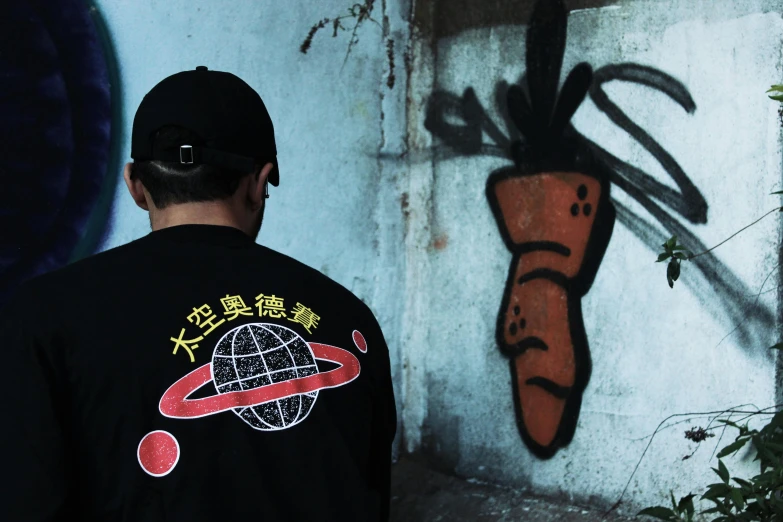 a man standing in front of a wall with graffiti on it, a cartoon, inspired by Li Tiefu, unsplash, wearing space techwear, with earth in the background, over looking saturn, long sleeves