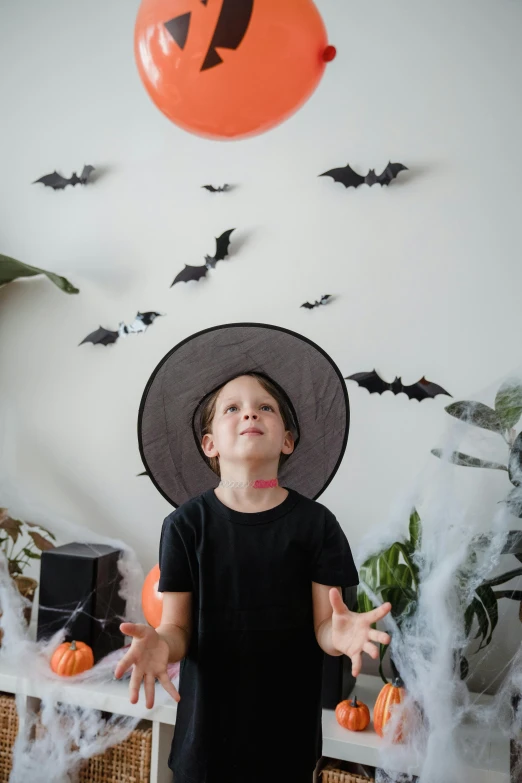 a young boy wearing a witch hat and holding a balloon, pexels contest winner, visual art, decoration around the room, bats, gif, multiple stories