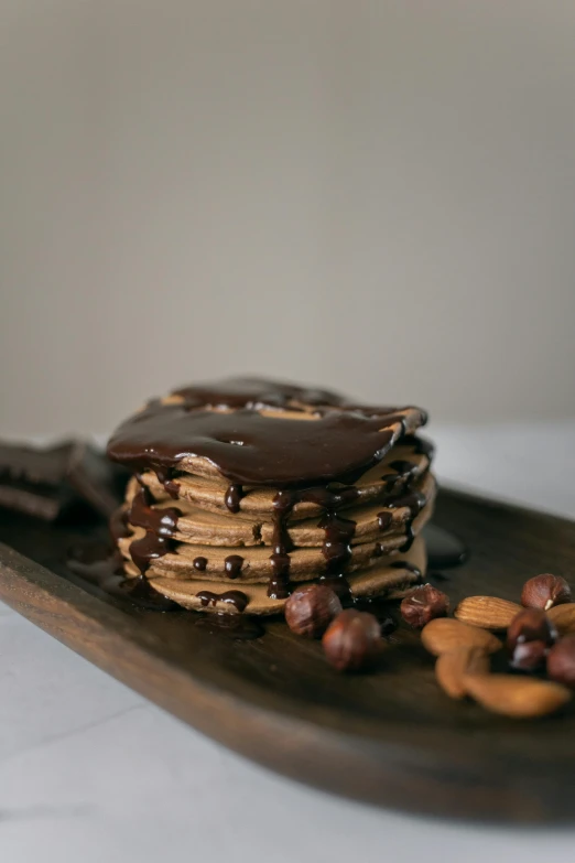 a stack of pancakes sitting on top of a wooden plate, dark chocolate painting, noot noot, nut, thumbnail
