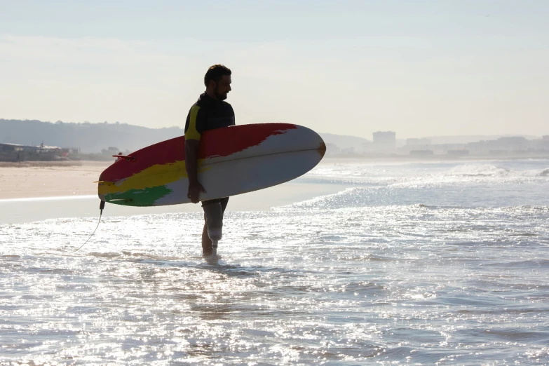 a man standing in the water holding a surfboard, by Nadir Afonso, plasticien, walking on the beach, avatar image