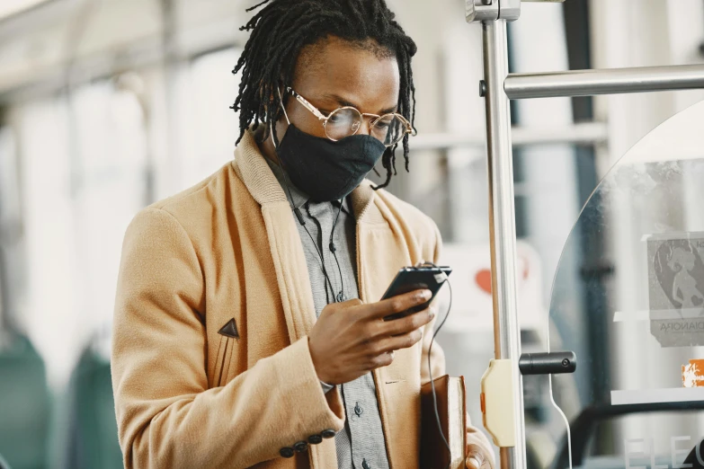 a man wearing a face mask looking at his cell phone, trending on pexels, afrofuturism, supersonic trains and passengers, brown, avatar image, australian