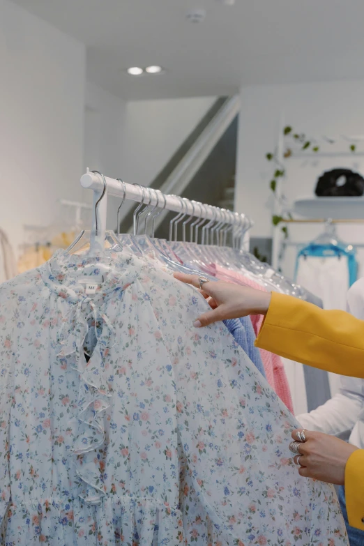 a woman standing in front of a rack of clothes, low quality video, clothes made out of flower, ecommerce photograph, gif