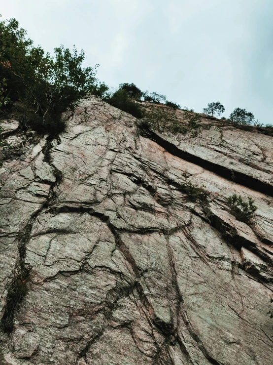 a man riding a snowboard up the side of a mountain, an album cover, by Elsa Bleda, unsplash, sōsaku hanga, large cracks, rock climbing, as seen from the canopy, jin shan