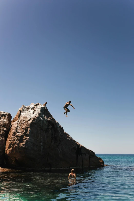 a person jumping off a cliff into the ocean, australian, rocks flying, mediterranean features, no crop