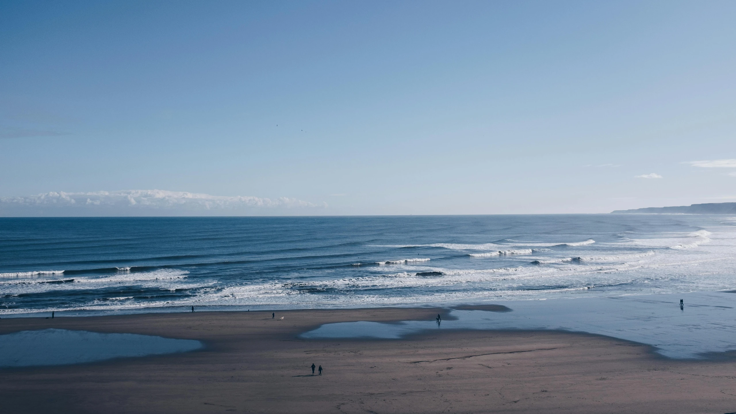 a group of people standing on top of a beach next to the ocean, minimalism, surfing, omaha beach, blue sand, vast expanse