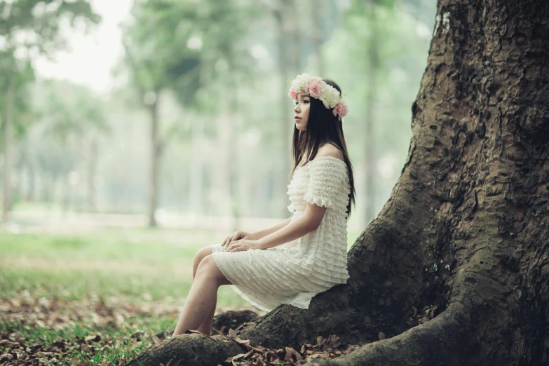 a woman in a white dress sitting under a tree, unsplash, romanticism, vietnamese woman, wearing a laurel wreath, unhappy, multiple stories