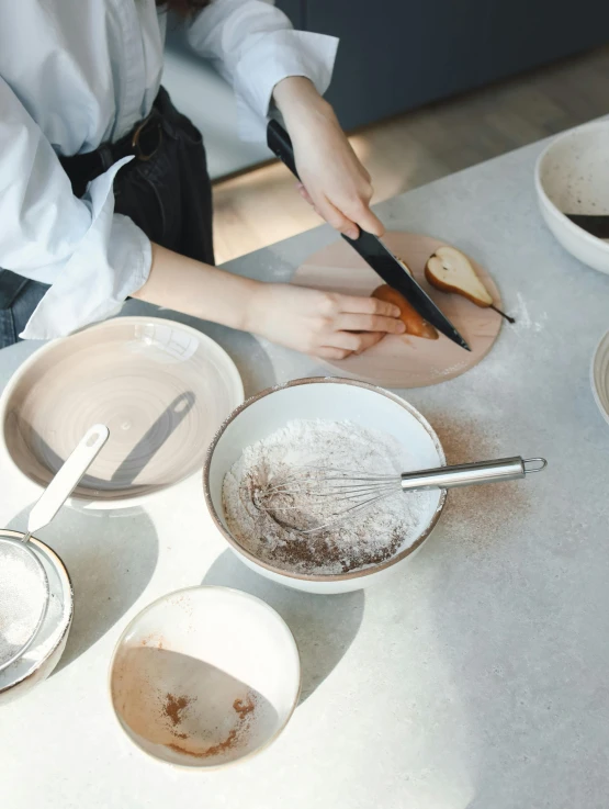 a woman is preparing food on a table, inspired by Yukimasa Ida, trending on unsplash, process art, brown and white color scheme, thumbnail, bakery, plating