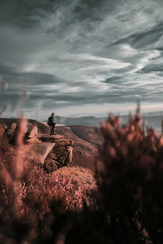 a person standing on top of a rocky hill, by Adam Marczyński, pexels contest winner, romanticism, eerie moorlands behind her, rich moody colour, during autumn, overlooking