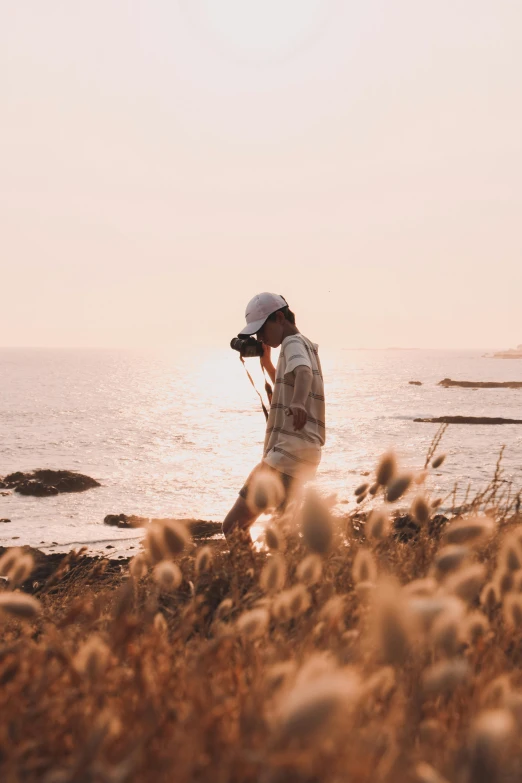 a man taking a picture of a body of water, a picture, unsplash contest winner, standing in the grass at sunset, coastal, various poses shooting photos, sunfaded