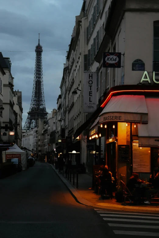 a street scene with the eiffel tower in the background, lights in distance, photo taken in 2018, square, cafe