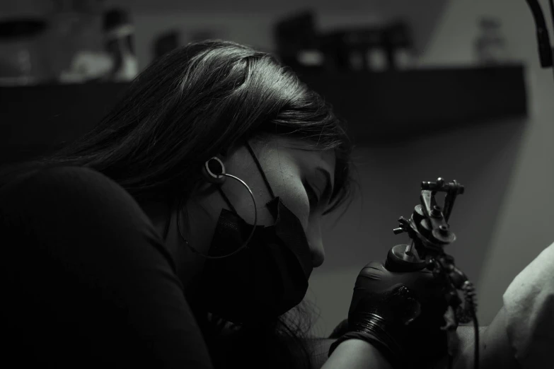 a black and white photo of a woman getting a tattoo, a tattoo, pexels contest winner, process art, vantablack chiaroscuro, profile image, gloves and jewelry. motion, desaturated color