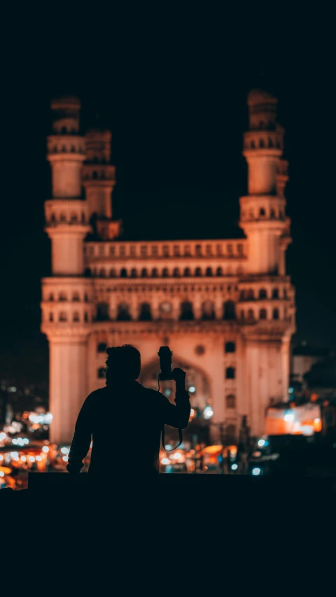 a man standing in front of a tall building at night, a statue, pexels contest winner, india, muslim, drinking, paisley