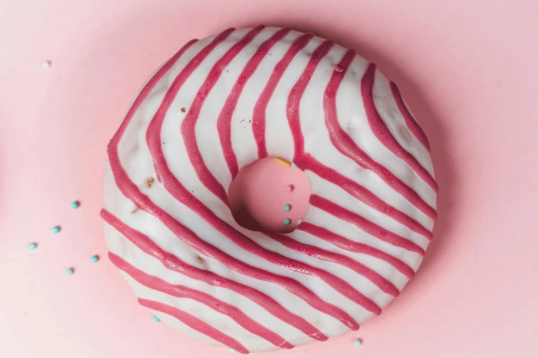 a pink donut with white icing and sprinkles, inspired by Louise Bourgeois, trending on pexels, white stripes all over its body, trending on dezeen, cinnabar, vivid lines