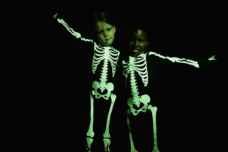 a couple of people standing next to each other in the dark, glowing bones, children, photorealist, 4 d
