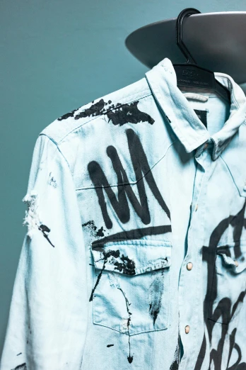 a close up of a shirt on a hanger, inspired by Jean Micheal Basquiat, trending on pexels, graffiti, double denim, studio shot, thumbnail, wearing a light blue shirt