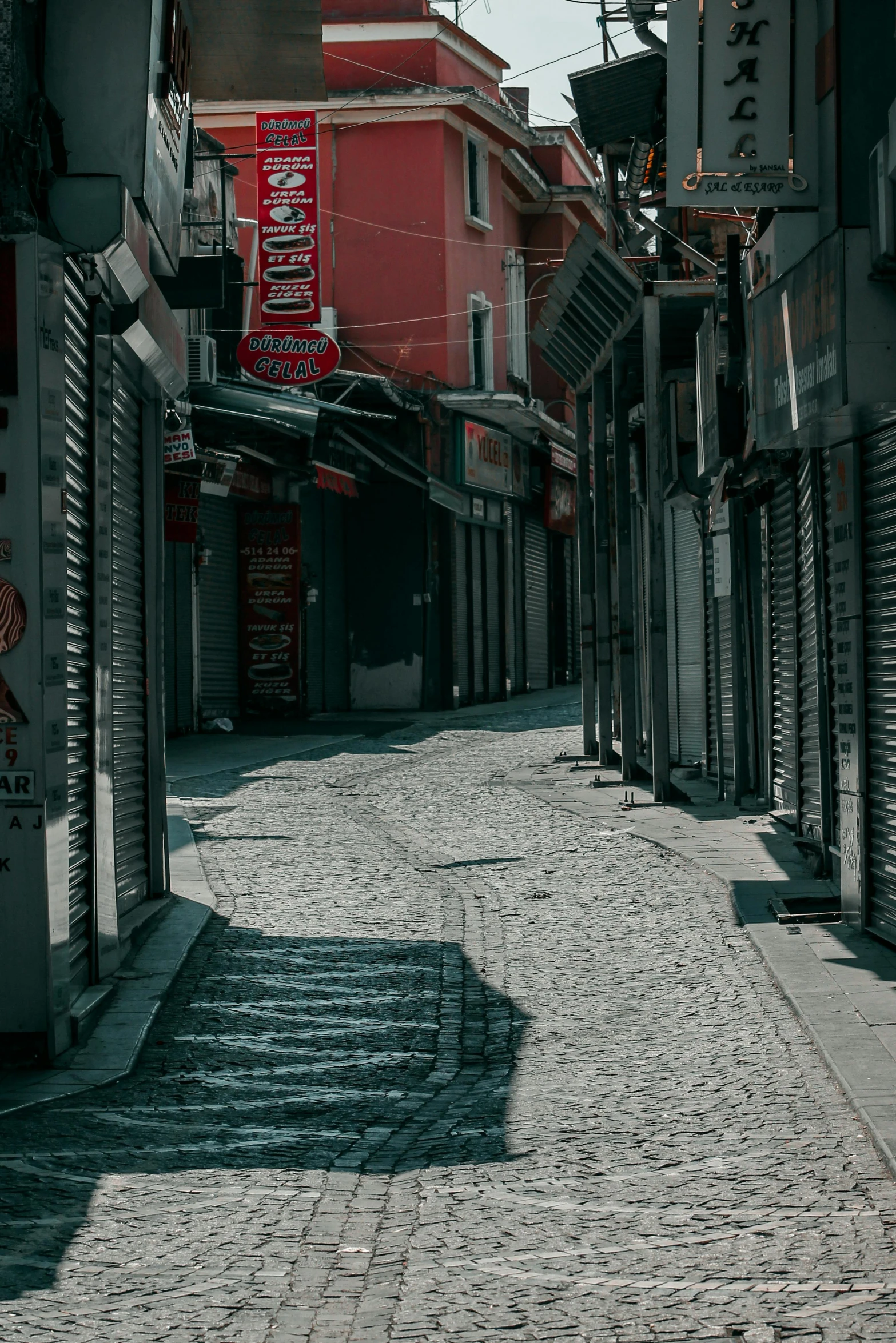 a person riding a skateboard down a cobblestone street, an album cover, by Alexis Grimou, storefronts, istanbul, quiet, photograph of the city street