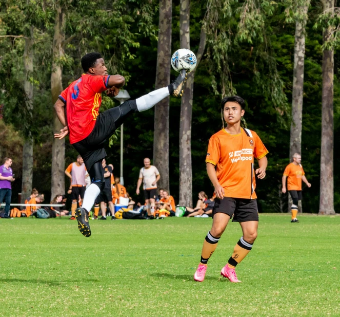 a group of young men playing a game of soccer, by Lee Loughridge, pexels contest winner, figuration libre, orange and black, sydney park, mana in the air, 💣 💥💣 💥