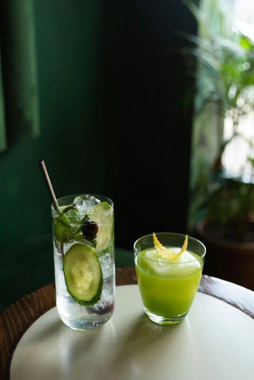 a couple of glasses sitting on top of a table, lush green, cucumber, bar, f / 2 0