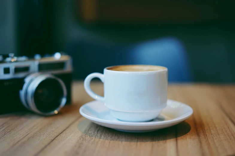 a cup of coffee and a camera on a table, by Peter Churcher, unsplash, photorealism, medium format. soft light, cafe, white, medium format