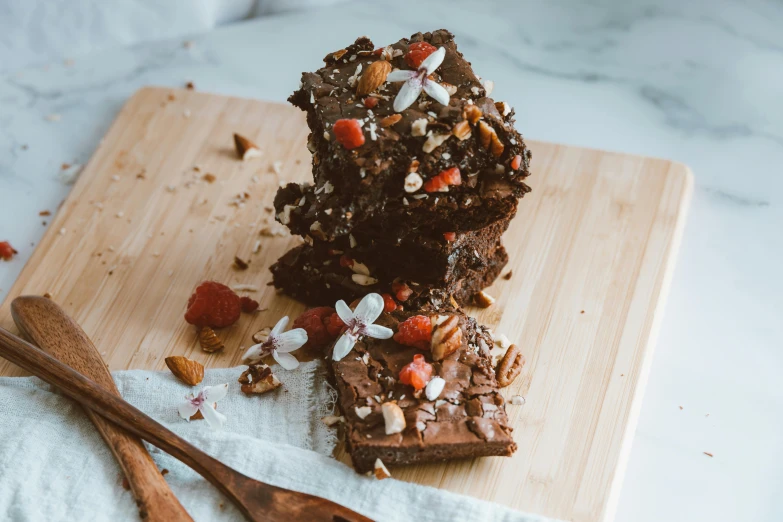 a couple of brownies sitting on top of a wooden cutting board, by Emma Andijewska, pexels contest winner, 🎀 🗡 🍓 🧚, rocky roads, botanicals, square