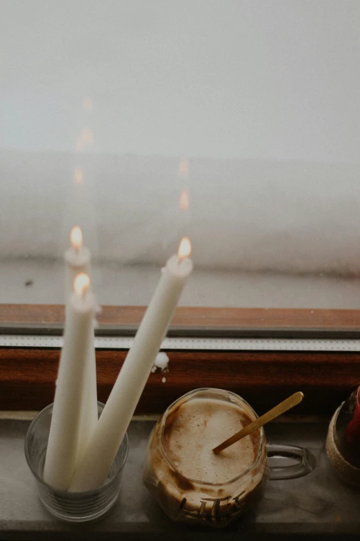 a couple of candles sitting on top of a window sill, by Jessie Algie, trending on unsplash, light and space, background image, brown, multiple stories, on a white table