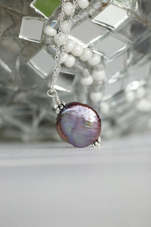 a close up of a necklace on a table, a picture, inspired by Perle Fine, purple aura, pearl silverplate, close up shot from the side, round-cropped