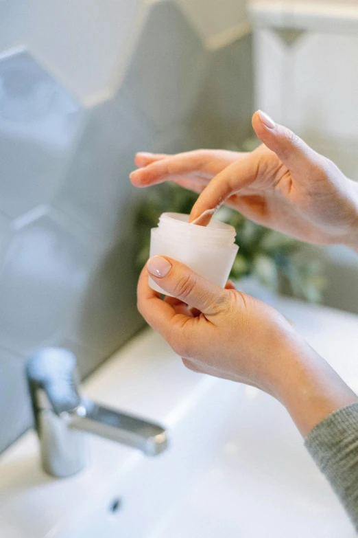 a woman using a hand sanitizer to clean her hands, unsplash, milk bath photography, jar on a shelf, profile image, manuka