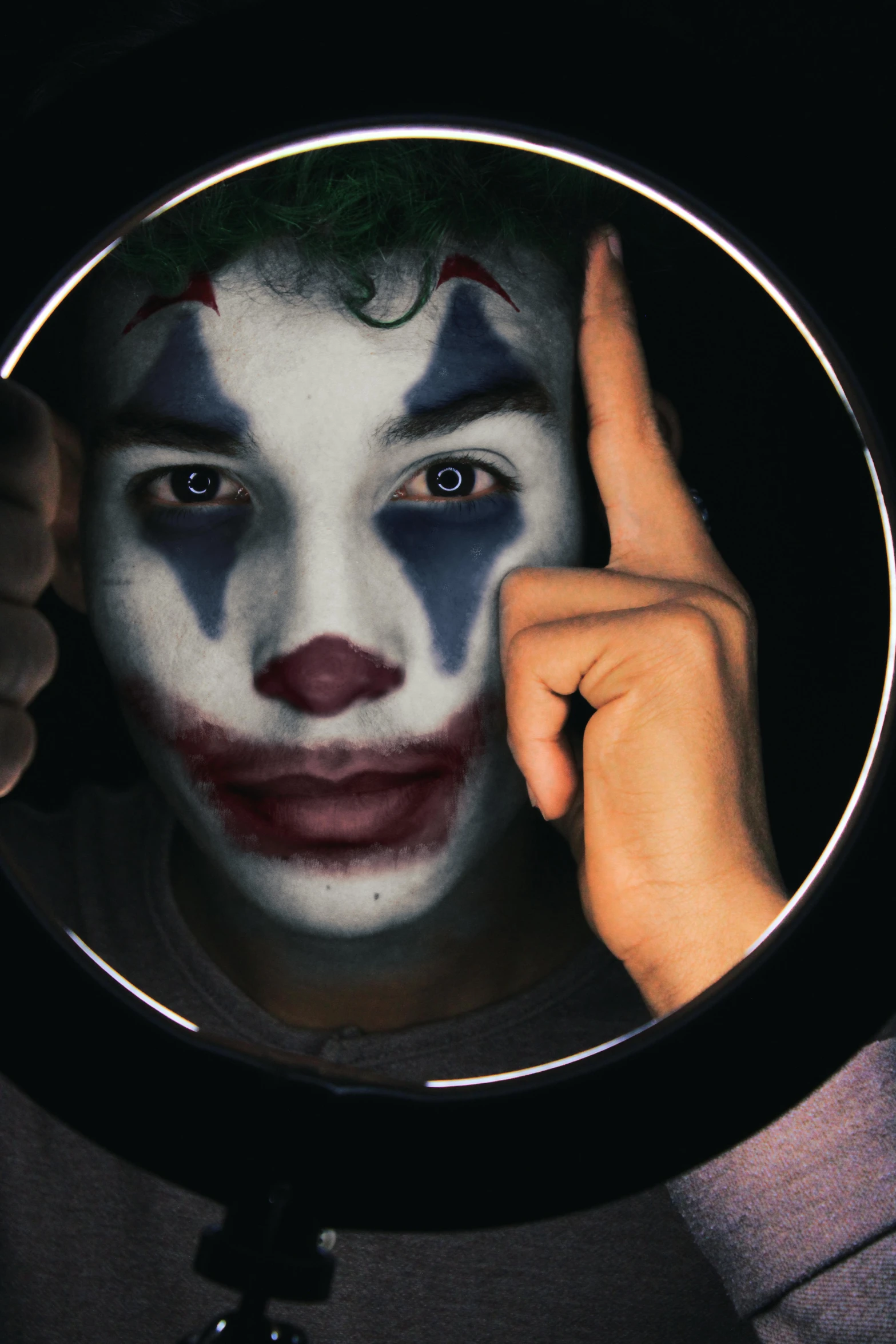 a close up of a person holding a mirror, trending on pexels, pop art, remarkable joker make up, teenage boy, ( ( theatrical ) ), dark night