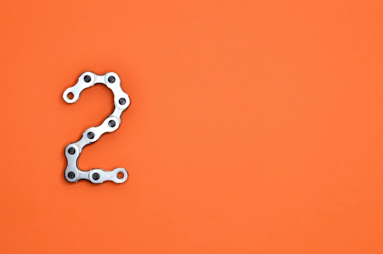 a bicycle chain on an orange background, unsplash, numerical, 2 2 years old, intricate mathematical shape, two