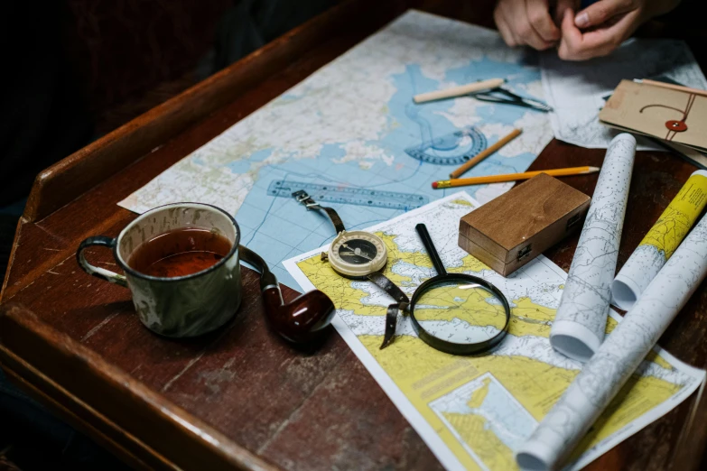 a person sitting at a table with a cup of tea and a pair of scissors, trending on unsplash, arts and crafts movement, nautical maps, explorers, magnifying glass, an escape room in a small