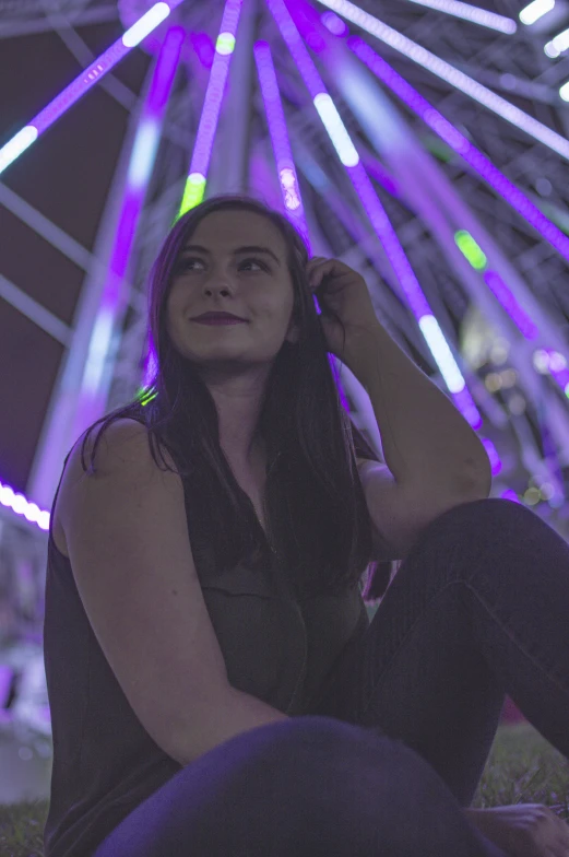 a woman sitting on the ground in front of a ferris wheel, purple laser lighting, young woman with long dark hair, profile image, slightly smirking