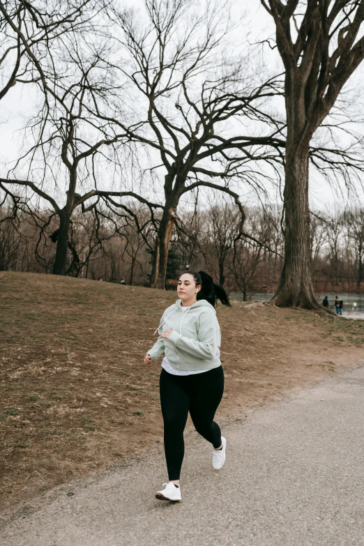 a woman running on a path in a park, by Kristin Nelson, plus-sized, central park, cold as ice! 🧊, infp young woman