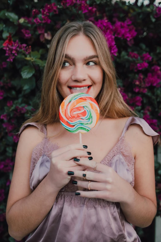 a woman holding a lollipop in front of her face, a colorized photo, trending on pexels, 👅 👅, smiling young woman, swirl, katelynn mini cute style