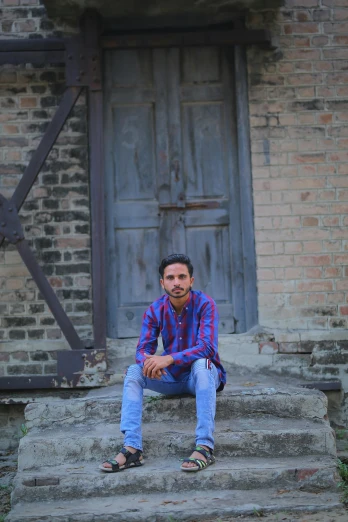 a man sitting on the steps of a building, by Rajesh Soni, cute pose, shabab alizadeh, in the countryside, full frame image