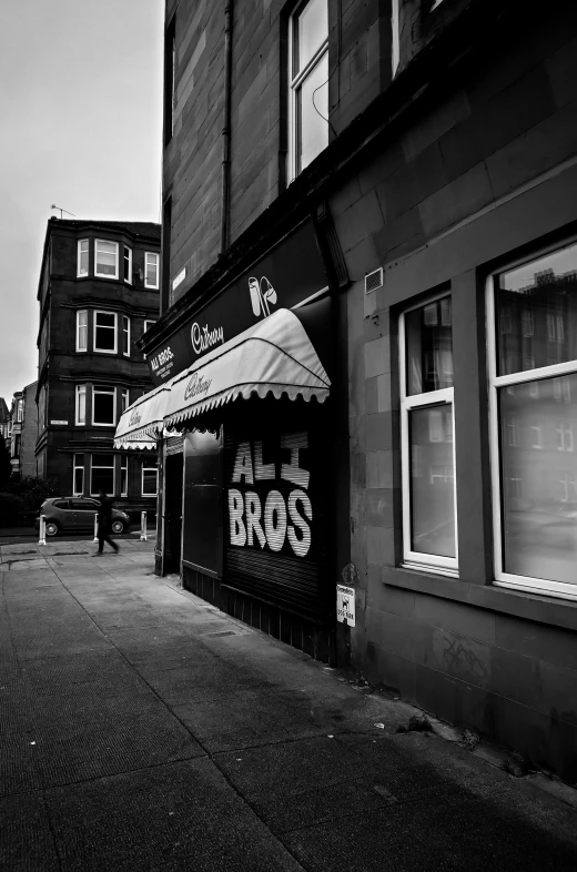 a black and white photo of a city street, a black and white photo, by Dave Allsop, lowbrow, scottish style, brothers, restaurant exterior photography, alternate album cover