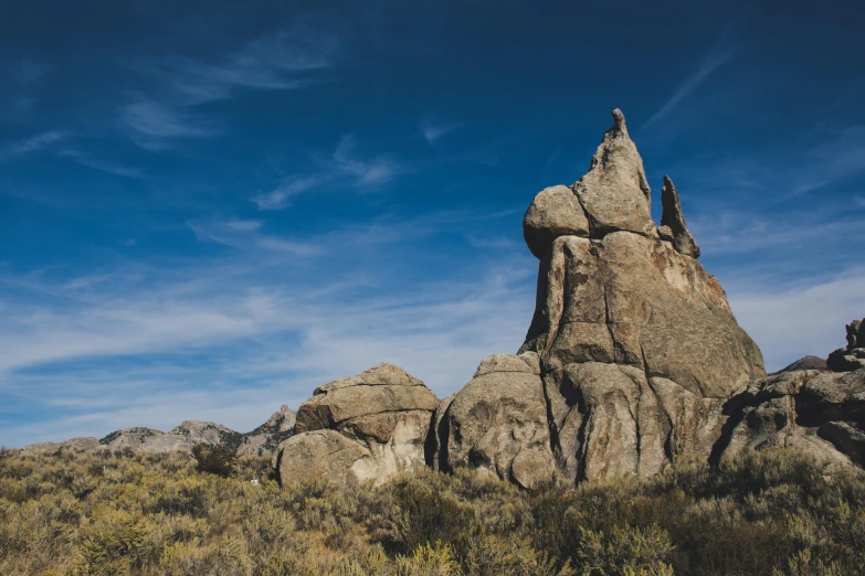 a large rock in the middle of a field, by Jeffrey Smith, unsplash contest winner, visual art, asymmetrical spires, mammoth, detail shot, blue sky