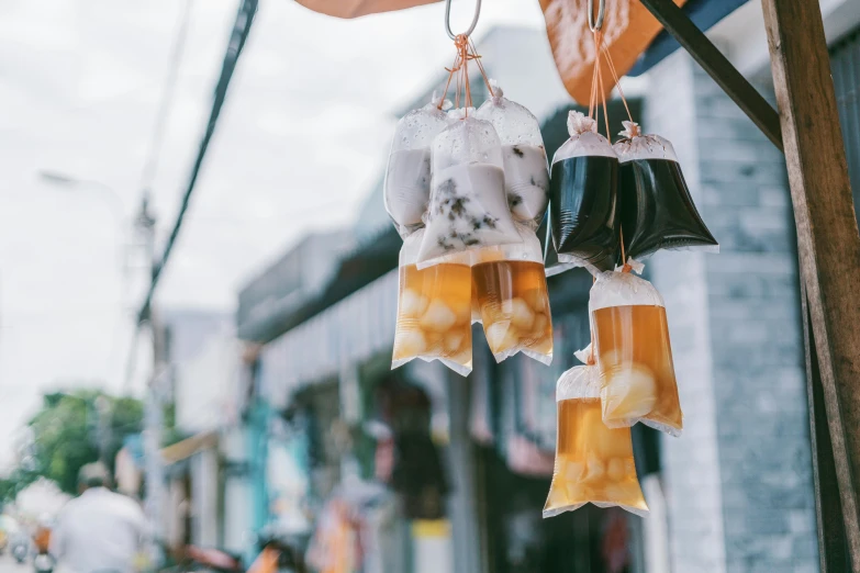 a couple of bags of food hanging from a pole, by Tan Ting-pho, trending on unsplash, carved soap, drink, taiwan, jelly