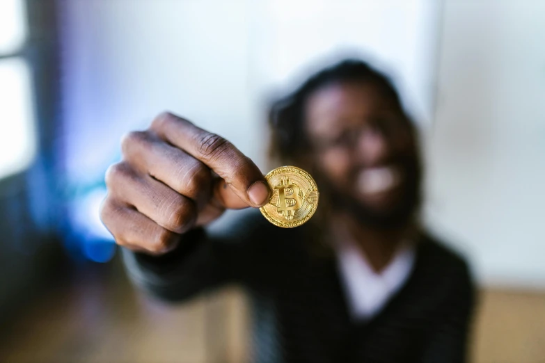 a close up of a person holding a coin, pexels contest winner, a black man with long curly hair, edible crypto, raising an arm, thumbnail