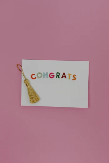 a congrats card with a tassel on a pink background, happening, rainbow accents, minimalist sticker, ots shot, small in size