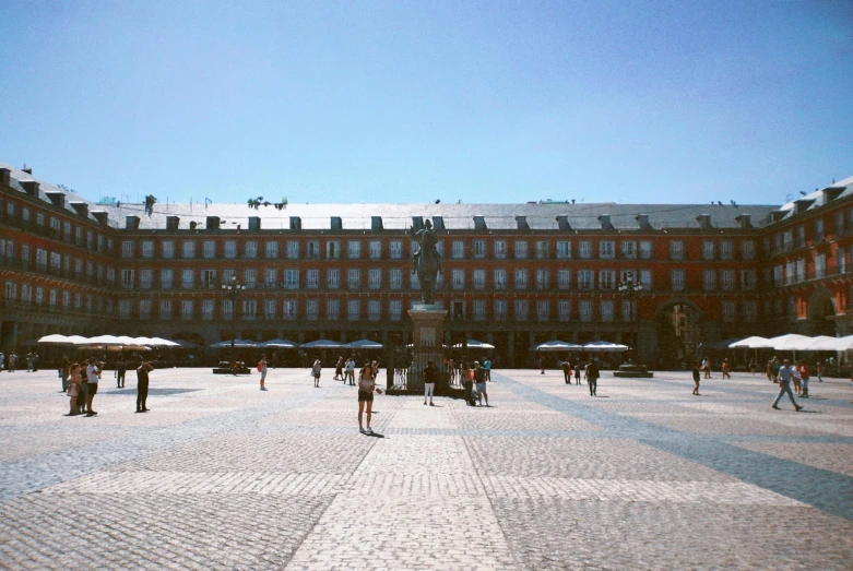 a group of people walking around a plaza, a picture, by Pablo Rey, pexels contest winner, clear blue skies, square, sunfaded, fransico goya